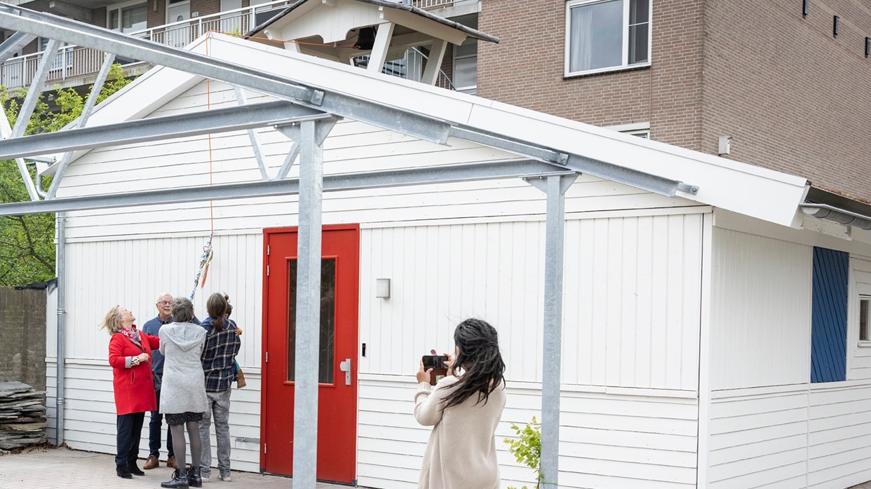 De voorziter en jongste en oudste bewoner van 't Rondeel luiden samen met de directeur van Woonbedrijf de teruggeplaatste schoolklok van de herbouwde Finse school